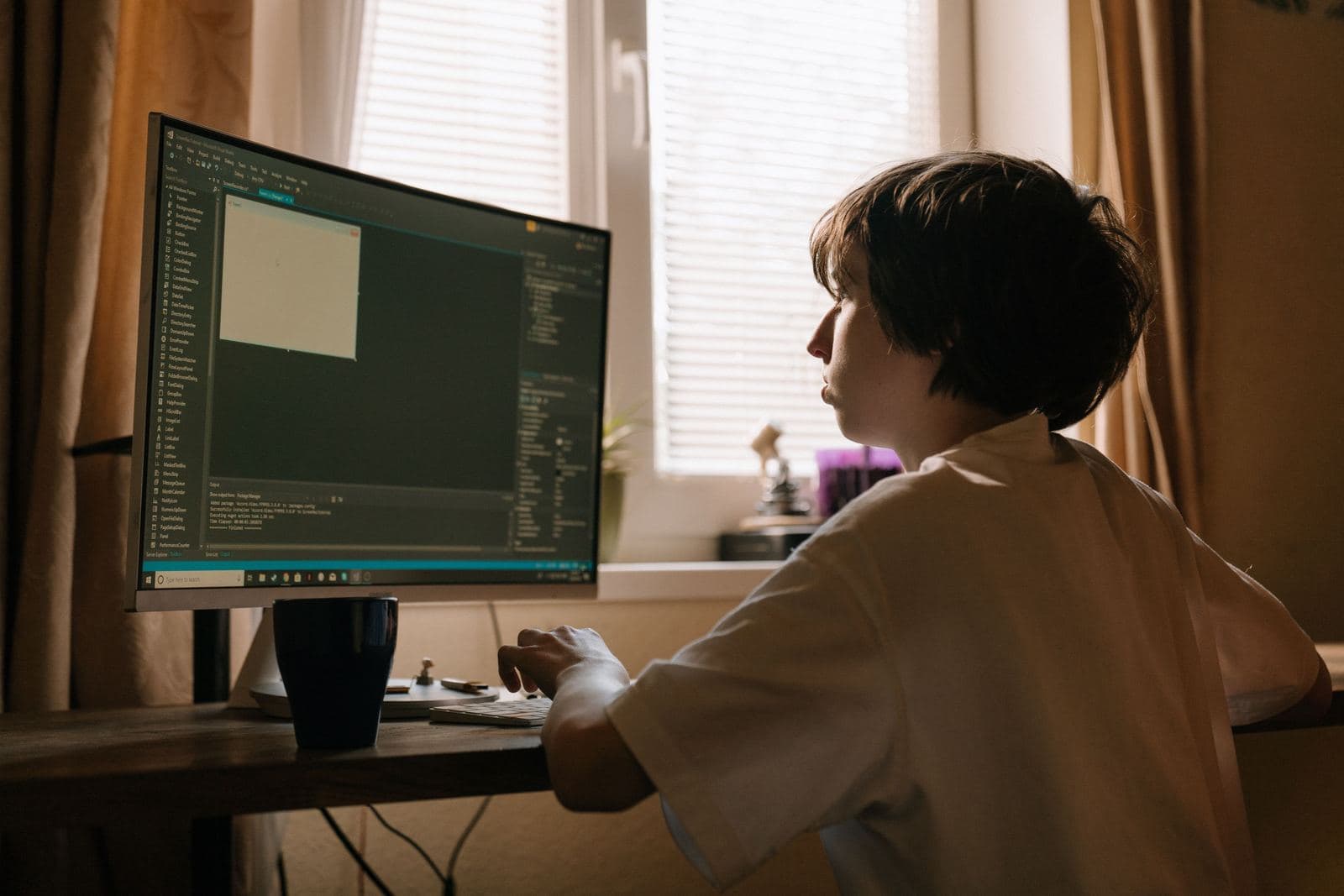 Dziecko siedzi przy komputerze i uczy się programować